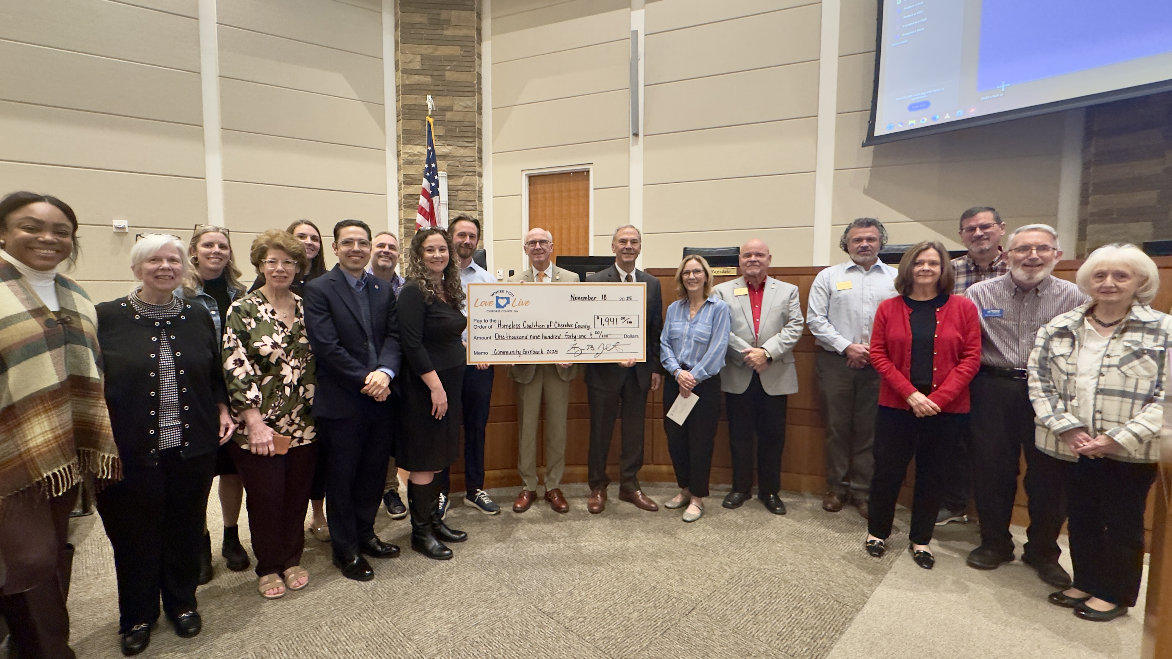 photo of about 17 people with a large check donating $1,941 to the Homeless Coalition of Cherokee County